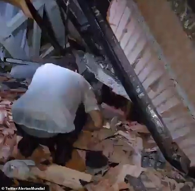 A wedding guest tries to help a person crawling under the rubble after the roof of a wedding venue in Colombia collapsed on Saturday evening.  Two people were killed