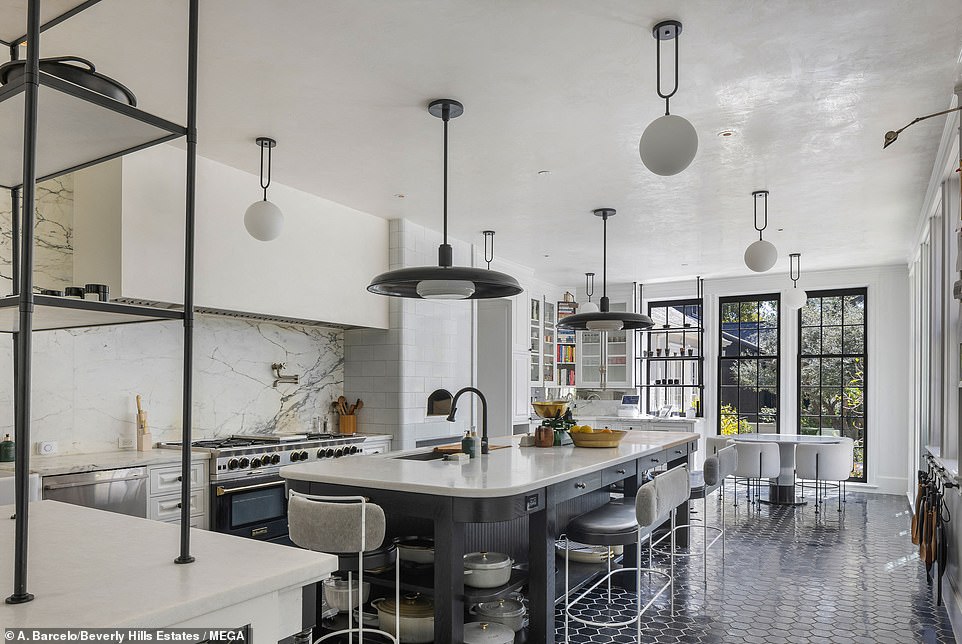 The kitchen is a chef's dream, with high ceilings, floor-to-ceiling windows, black tile floors and a huge island