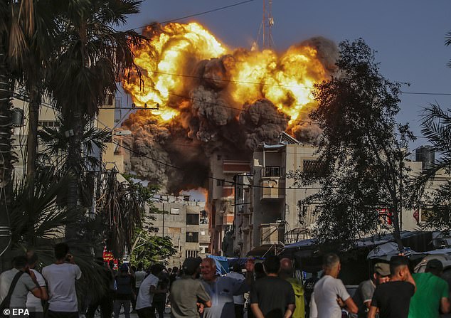 Palestinians watch in horror as an Israeli airstrike destroys a building in the Al Bureije refugee camp