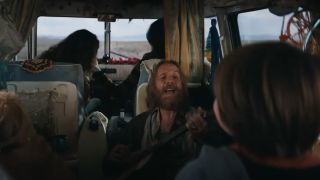 Rhys Ifans' unnamed character strums a guitar in a camper in Venom: The Last Dance