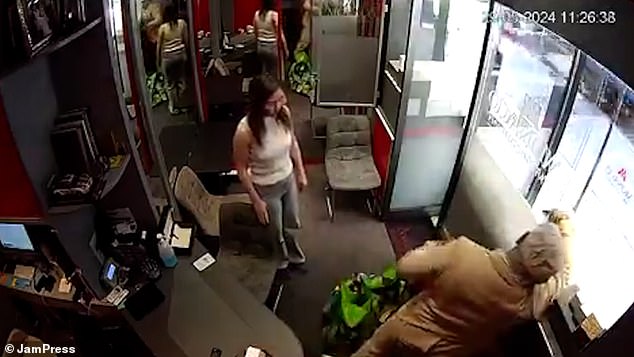 The store clerk looks visibly nervous as the robber continues to grab watches from the window