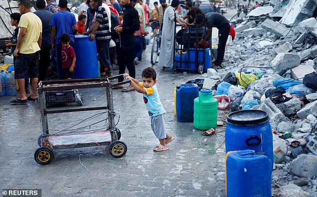 A Palestinian child stands next to water containers amid the ongoing conflict between Israel and Hamas