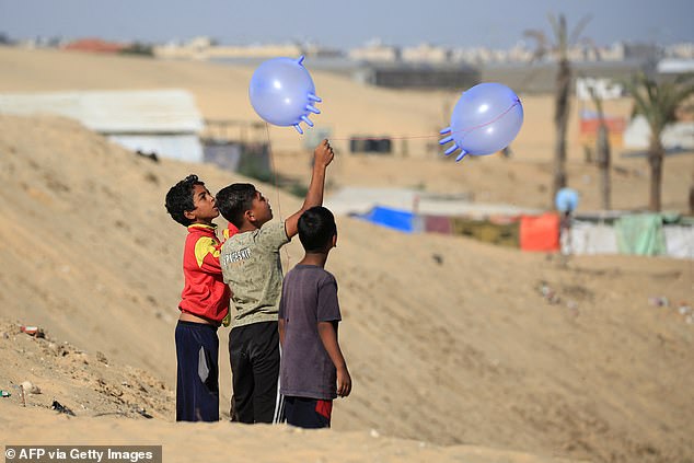 Displaced Palestinian children play with surgical rubber gloves in Rafah in the southern Gaza Strip