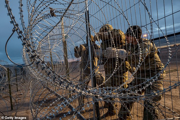 The order could block illegal immigration at the southern border once apprehensions reach a certain threshold per day.  Pictured: Texas National Guard members install barbed wire border fencing in El Paso on April 2