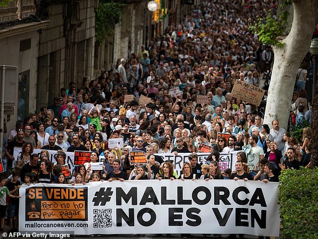 Protesters hold a banner reading 'Mallorca is not for sale' during a demonstration to protest mass tourism and house prices