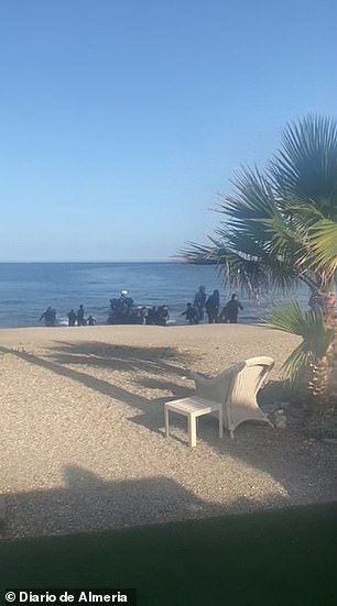 Migrants are seen running onto the sandy beach as they disembark in Almeria