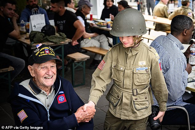 US paratrooper veteran George Cross, 99, shares a moment with a young child on the 80th anniversary of the historic land invasion