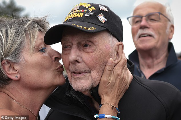 Gene Kleindl, a 102-year veteran of the historic day, gets a kiss Tuesday while visiting the Normandy American Cemetery