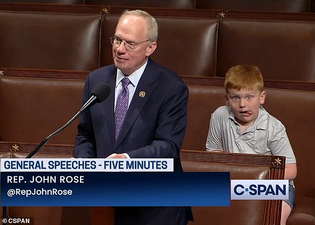 Behind Rose, 59, sat his son, Guy, 7. As Rose spoke into the microphone, his son smiled at the camera, before crossing his eyes, sticking out his tongue and making a series of funny faces and hand gestures.