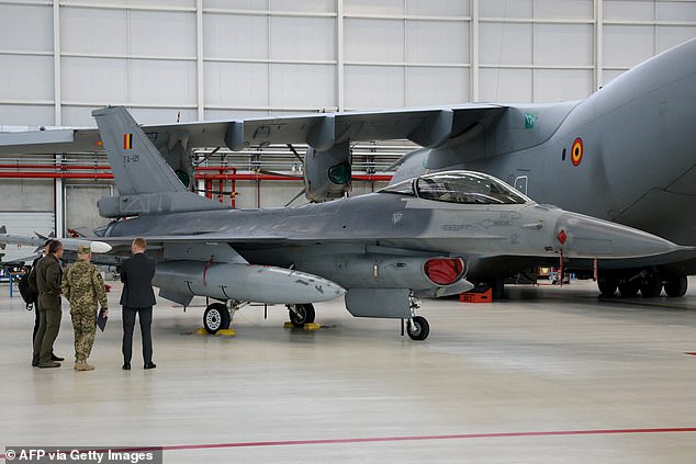 A Ukrainian army stands with people next to F-16 fighter jets during an inspection visit by the Ukrainian president to Belgium in an agreement to help Kiev fight the Russian invasion, at the Melsbroek military airport in Steenokkerzeel, northeast of Brussels on May 28 2024