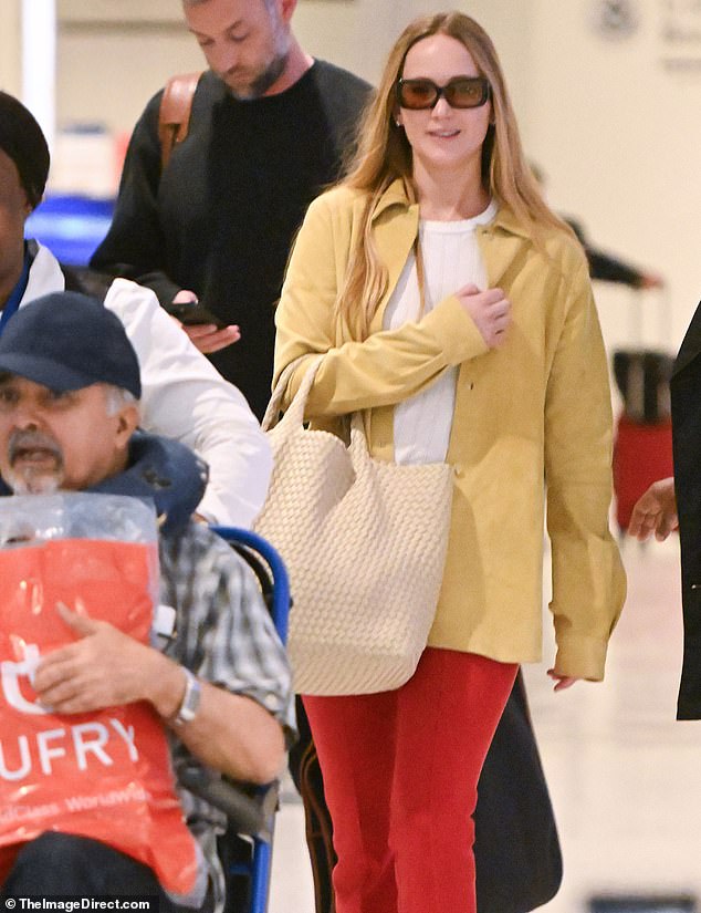 Lawrence paired her unconventional shoes with an otherwise stylish outfit, arriving in a loose overshirt and statement red fitted trousers.