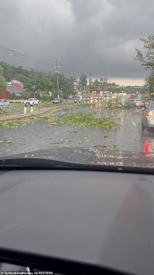 Vehicles pass fallen leaves and branches on a road as storms hit Gaithersburg, Maryland