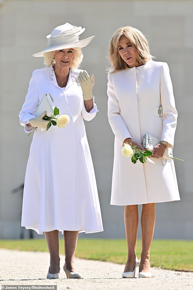 The Queen and France's First Lady, both dressed in white, looked solemn as they prepared to lay some flowers