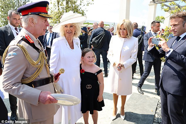 President Macron was seen taking a photo of the King and Queen with a young fan