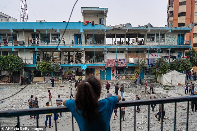 A Palestinian girl watches as others check a UN school building displacing people affected by the Israeli bombardment of Nuseirat