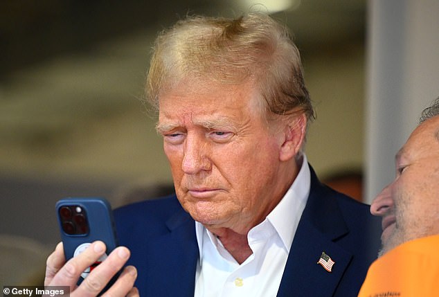 Donald Trump looks at his phone while visiting the F1 Grand Prix race in Miami, Florida