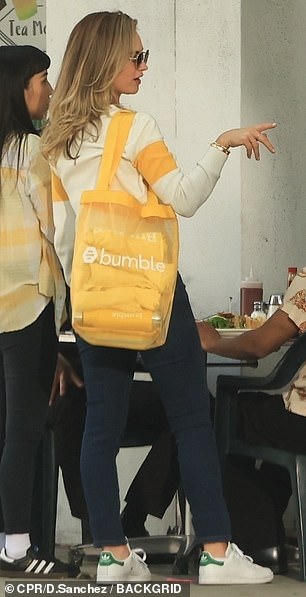 She wore a chic white sweater with a yellow stripe on the chest and the Bumble logo in black