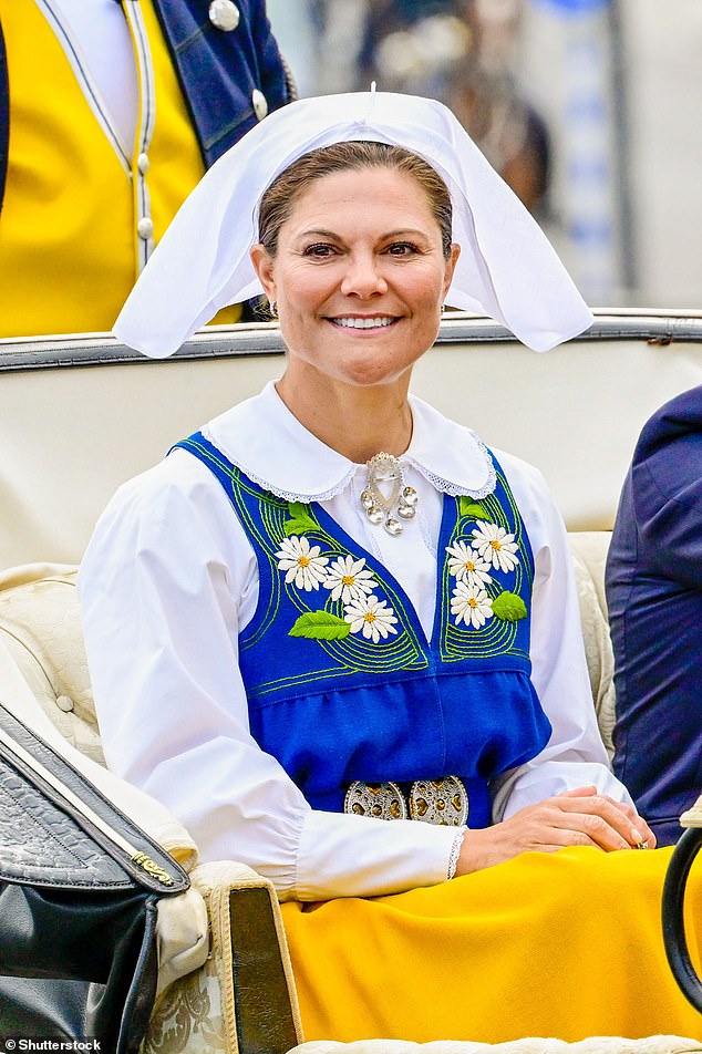 Crown Princess Victoria wore a traditional dress consisting of a white blouse with a blue tabard embroidered with flowers, a yellow overskirt and a white headscarf