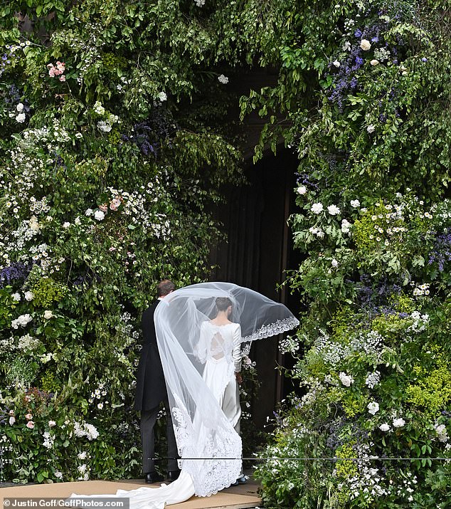 Olivia walks through the beautiful floral arch at the entrance to the cathedral