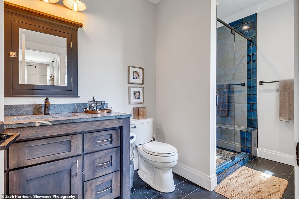 One of the bathrooms has a dark tiled floor and dramatic mahogany drawers and mirror