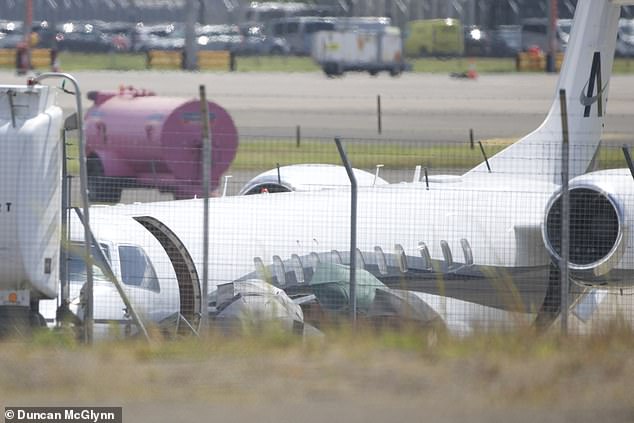 Taylor was obscured by black umbrellas as she exited the plane