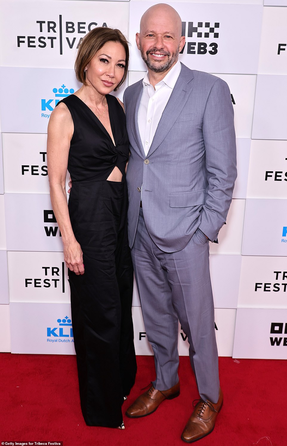 Jon looked dapper at the premiere in a silver suit worn without a tie as he posed next to his black-clad wife Lisa Joyner