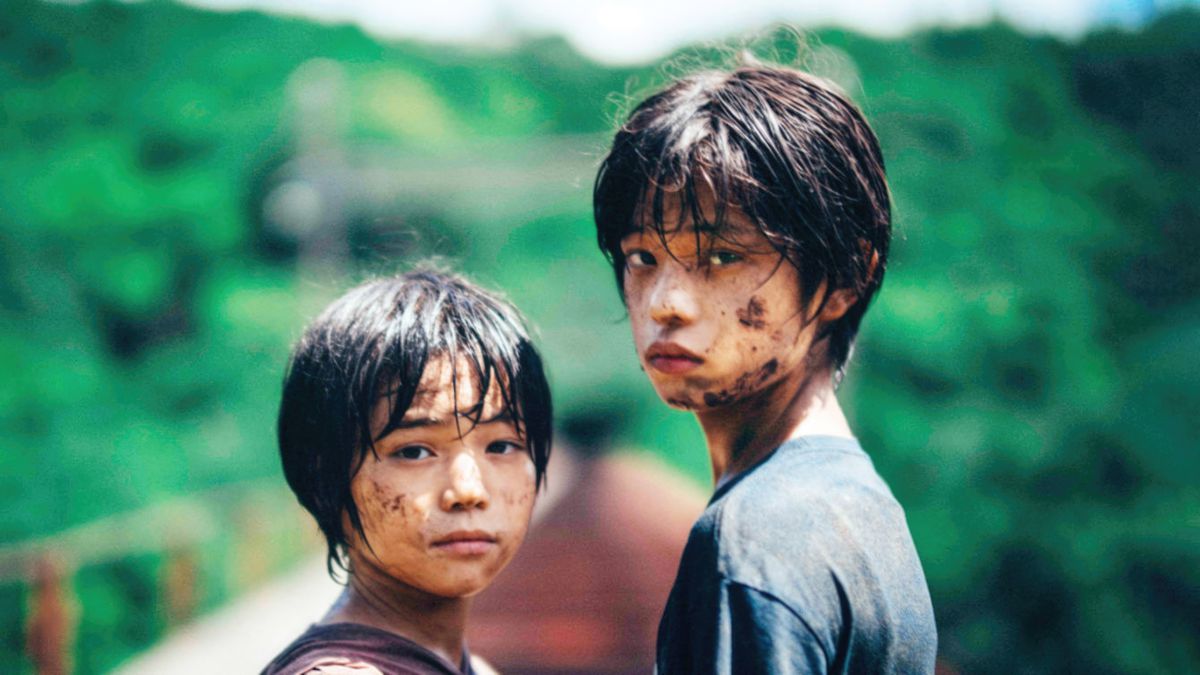 Two young Japanese children covered in dirt, looking at the camera