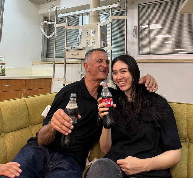 Noa laughs as she drinks a Coke with her father Yakov after being reunited on Saturday