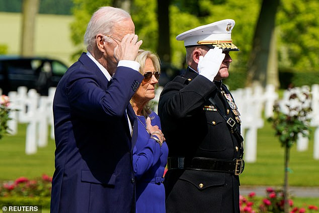 President Joe Biden salutes and first lady Jill Biden has her hand on her heart as Taps plays at the Aisne-Marne American Cemetery in Belleau, France