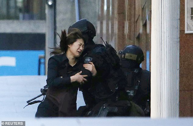 A hostage is pictured running towards a police officer outside the Lindt Cafe in Sydney on December 15, 2014