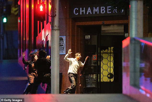 People are pictured running out of the Lindt Café with their hands up on December 16, 2014