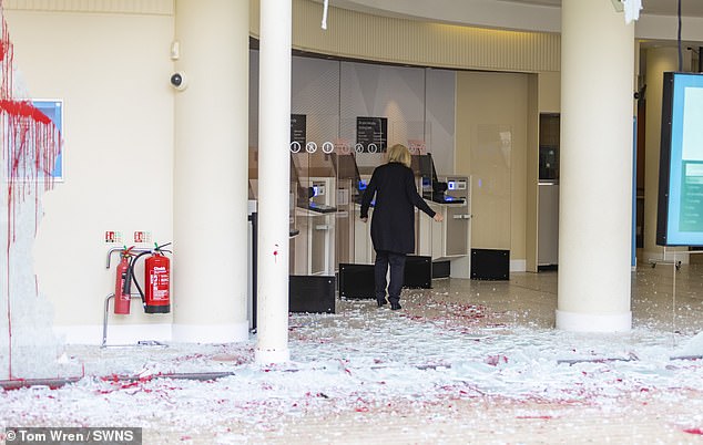 BRISTOL: A woman carefully makes her way over the shattered and stained broken window glass