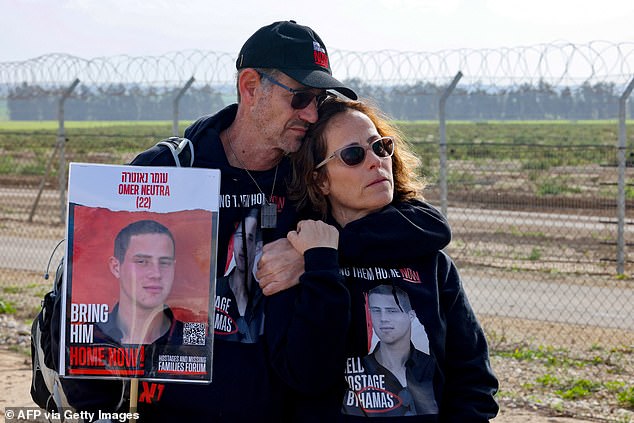 Relatives of Israeli hostages held by the Palestinian Hamas movement carry a photo of Omer Neutra, 22, in Kibbutz Nirim along the Gaza border fence on January 11, 2024