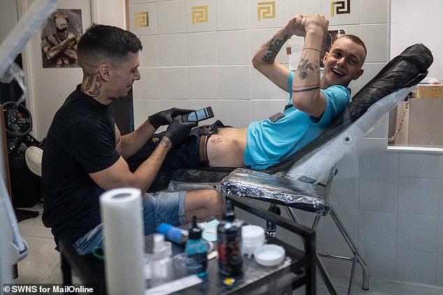 We see a man cheering after getting a tattoo in a salon in Magaluf last weekend