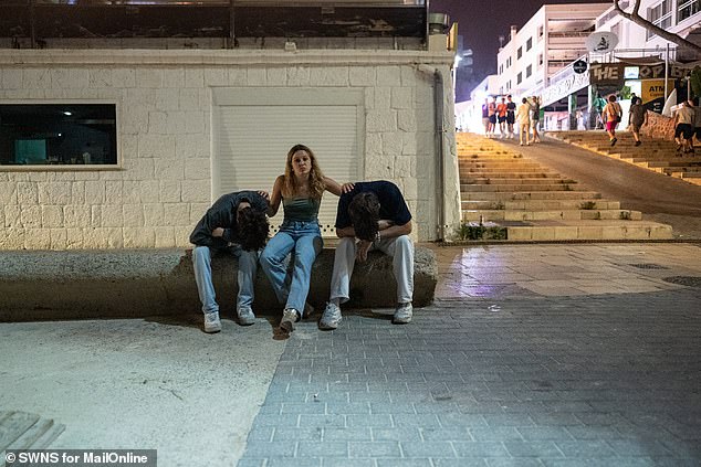 A woman is seen caring for two men who are looking a bit worse for wear in Magaluf