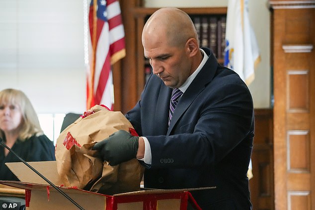 Proctor opens an evidence box to show the jury a broken taillight while testifying