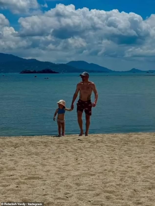 Jamie walks along the beach holding his youngest daughter Olivia's hand