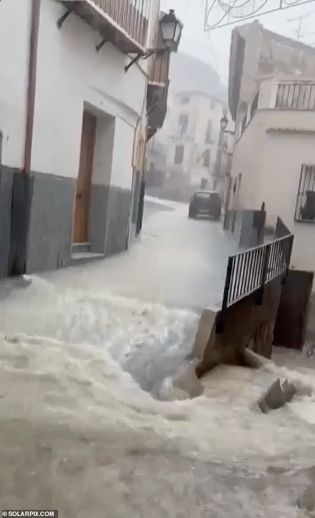 Water flows down a street in Murcia amid rain showers on Monday