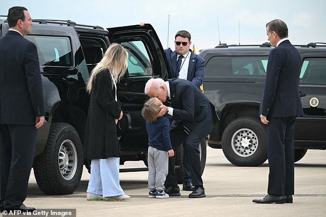 President Joe Biden gives a kiss to his grandson, baby Beau, the son of Hunter Biden (right) and his wife Melissa Cohen (left)