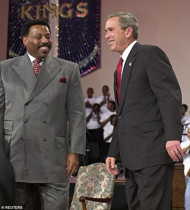 President George W. Bush listens to applause with Reverend Tony Evans at the dedication of Oak Cliff Bible Fellowship's Youth Education Center, October 29, 2003 in Dallas, Texas