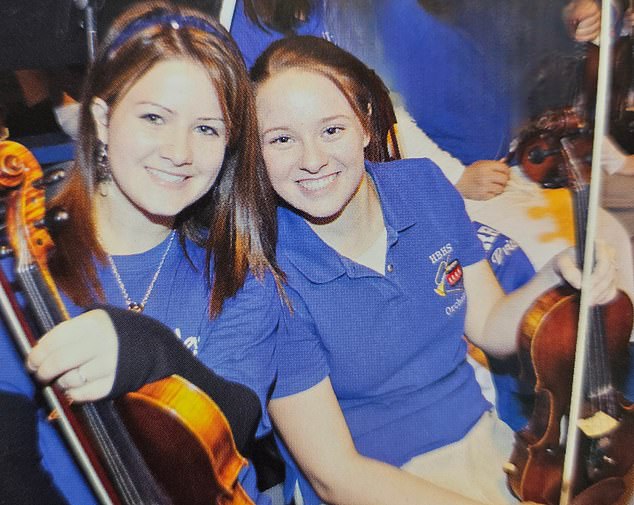 Moore pictured with a friend, in her school's orchestra in their senior year