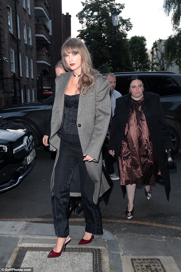 Taylor looked stunning in a black corset, layered under a custom gray coat and accessorized with a choker necklace and sky-high heels that matched her lipstick color