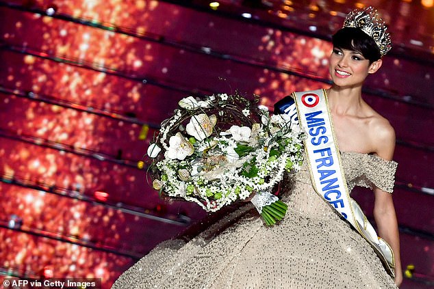 Eve Gilles poses on stage with her crown and a bouquet of flowers after her victory