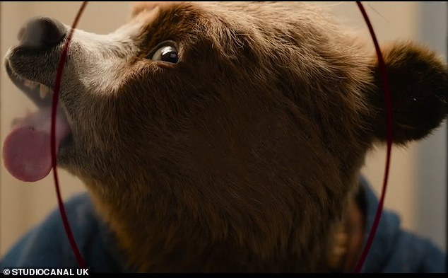 As the trailer opens, Paddington struggles to get a grip on the photo booth as he tries to pose for his passport photo.