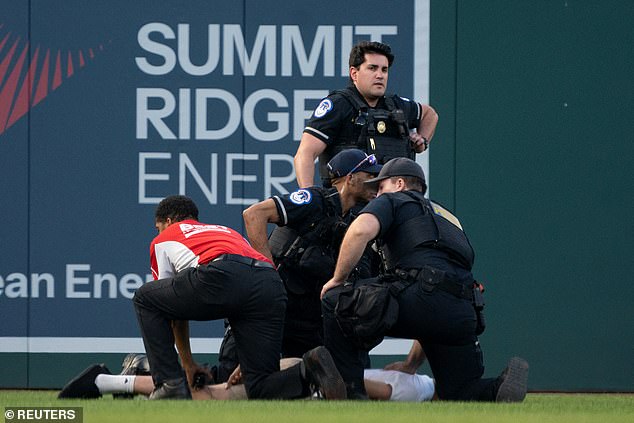 Three police officers and a security guard try to stop a climate change protester