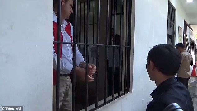 The father of two, wearing a white dungaree, brown chinos and a red prison vest, did not answer questions from waiting journalists and hid his face in the corner of a cell