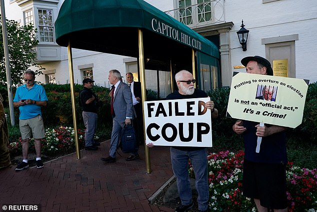 People hold signs outside the Capitol Hill Club ahead of a meeting with House Republicans and Trump