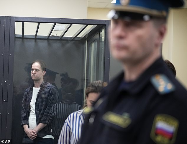 Wall Street Journal reporter Evan Gershkovich, left, stands in a glass cage in a courtroom at the First Court of Appeal of General Jurisdiction in Moscow