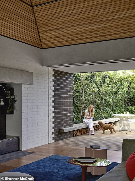 Separated from the main house by an internal herringbone stone path, the beautiful living room is a unique gray brick structure in which a timber-clad, sloping ceiling rises to a skylight to allow sunlight to stream in.