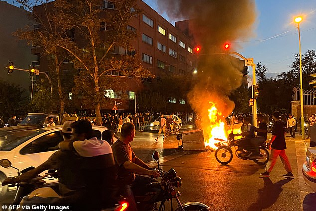 Iranian demonstrators set fire to a barricade during a protest for Mahsa Amini, a woman who died in custody after being arrested by the republic's 'morality police', in Tehran, September 2022
